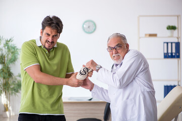 Obraz premium Young male patient visiting old male doctor in expensive medicin