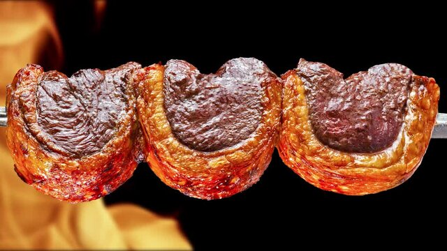 Picanha, traditional Brazilian barbecue with fire background.