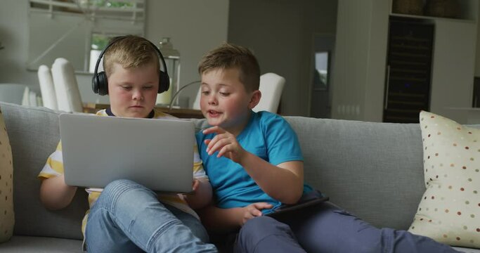 Caucasian boy with his brother sitting in living room and using laptop