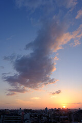 Fototapeta premium 兵庫県神戸市東灘区の高層マンションの上層階からの夜明け。大阪生駒山から太陽が昇り、あたりはオレンジ色に染まり、ビル群がシルエットで浮かぶ。