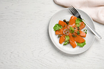 Salmon carpaccio with capers, lettuce, microgreens and onion on white wooden table, flat lay. Space for text