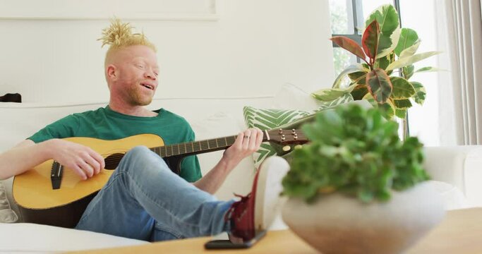 Albino african american man with dreadlocks playing guitars and singing