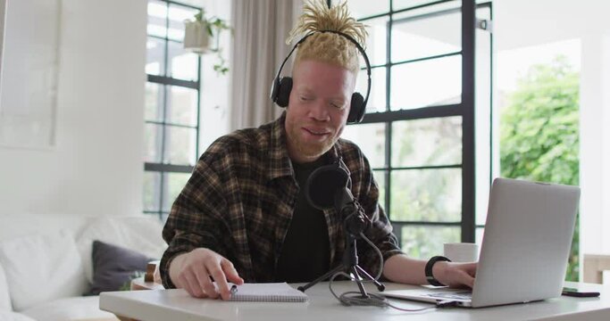 Happy albino african american man with dreadlocks making podcast