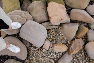 feet on the seashore. a traveler in sneakers stands on a rocky shore near the Japanese sea.