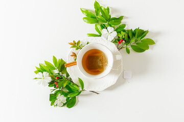 Cup of tea and plant leaves composition on white background. Flat lay, top view. 