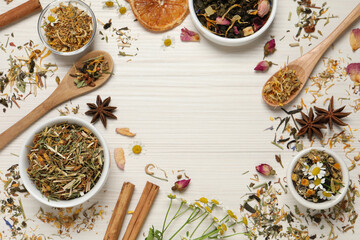 Frame of different dry teas on white wooden table, space for text