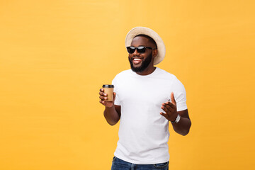 Stylish young african american man holding cup of take away coffee isolated over yellow background.