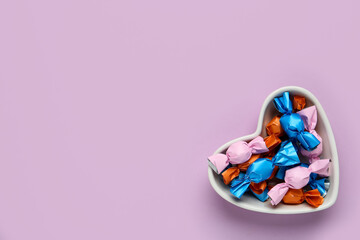 Candies in colorful wrapper on pink background, top view. Space for text