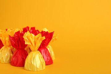 Candies in colorful wrappers on yellow background. Space for text