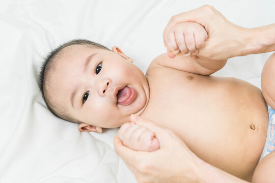 Cute asian happy 5 months baby boy.Mother's hand playing with her son in the bedroom.little kid relaxing at home.Lifestyle.top view. Space for text.