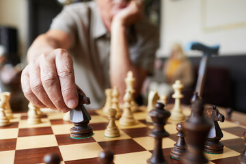 Close up of Caucasian senior man playing chess and enjoying activities in nursing home, copy space