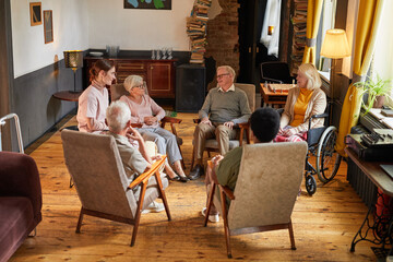 Fototapeta na wymiar Full length view at group of senior people sitting in circle during therapy session at retirement home, focus on woman crying, copy space