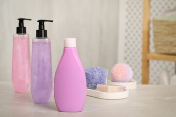 Obraz na płótnie Canvas Bottles of shower gel on light table in bathroom, space for text