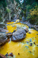 Vertical of mineral water river of yellow at bottom of deep canyon