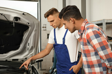 Mechanic and client near car at automobile repair shop