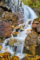 Close-up view of small waterfall over red and brown rocks