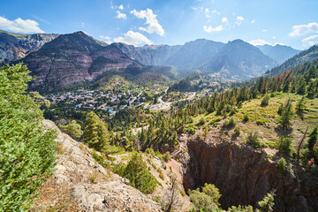 Small town surrounded by mountains from overlook above walking bridge and canyon