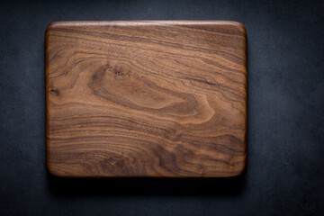 Black walnut handmade wooden chopping board. Handmade black walnut wooden cutting board on dark tone texture background.