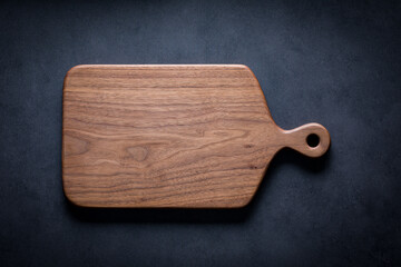 Black walnut handmade wooden chopping board. Handmade black walnut wooden cutting board on dark tone texture background.