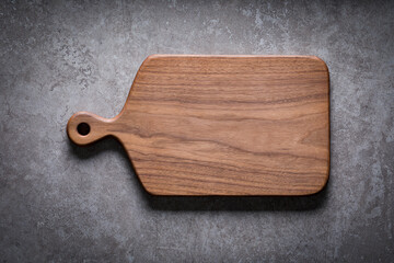 Handmade black walnut wooden cutting board on cement textured tabletop. Walnut wooden chopping...