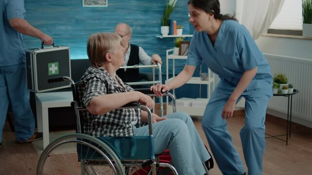 Invalid old woman in nursing home receiving medical visit for checkup from nurse. Medical assistant doing consultation for patient with disability in wheelchair. Person with handicap