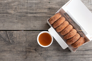 Cup of apple cider and half dozen of cinnamon donuts on wooden table