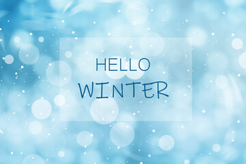 Phrase Hello Winter and snowfall on light blue background, bokeh effect