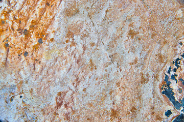 Texture of rock up close with rust colors and dark gray spots