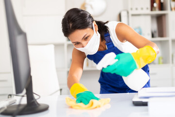 Fototapeta na wymiar Female cleaner working in protective mask productively on task in office
