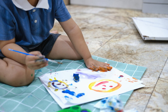Focus on hands on paper, early childhood learning by using paints and brushes to build imagination and enhance skills on the board.