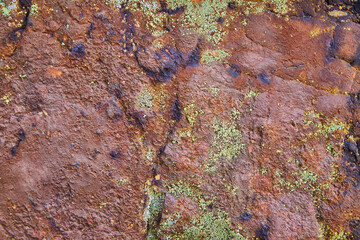 Texture of rock wall of red with patches of lichen