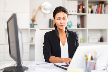 Smiling woman working with papers and laptop in office