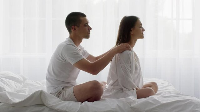 Caring man giving relaxing body massage to his wife in bed