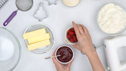Christmas shortbread cookies with raspberry preserves recipe. Ingredients for baking needs close up on kitchen table, view from above