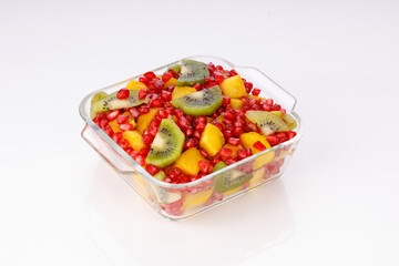 Mixed cut fruits arranged in a transparent glass bowl  with white background, isolated.