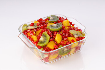 Mixed cut fruits arranged in a transparent glass bowl  with white background, isolated.