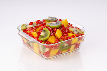Mixed cut fruits arranged in a transparent glass bowl  with white background, isolated.