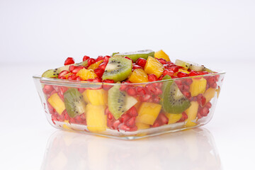 Mixed cut fruits arranged in a transparent glass bowl  with white background, isolated.