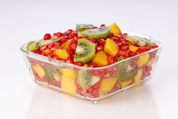 Mixed cut fruits arranged in a transparent glass bowl  with white background, isolated.