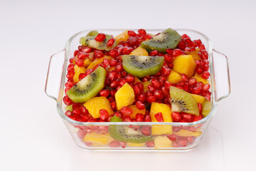Mixed cut fruits arranged in a transparent glass bowl  with white background, isolated.