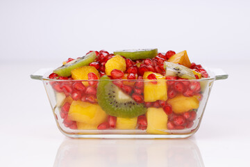 Mixed cut fruits arranged in a transparent glass bowl  with white background, isolated.