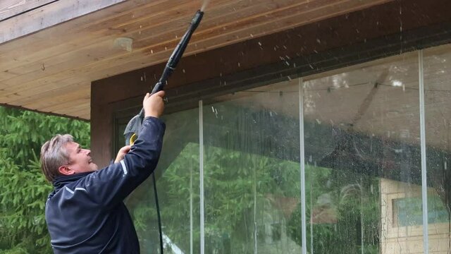 Man cleaning walls and floor with high pressure power washer. Washing terrace wood planks and cladding walls. High quality 4k footage