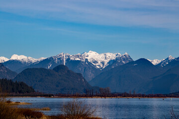A view of a wide river with snow capped mountains in the background