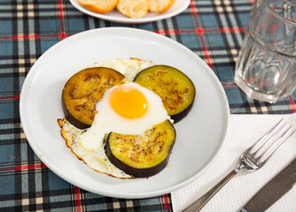 Fried sunny side up eggs with sliced eggplant for lunch in canteen. Public catering ovo-vegetarian food concept..