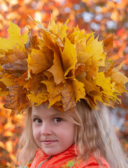 Autumn. Portrait of a girl with a wreath of yellow fallen maple leaves on her head in autumn colors. 