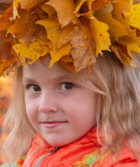 Obraz na płótnie Canvas Autumn. Portrait of a girl with a wreath of yellow fallen maple leaves on her head in autumn colors. 