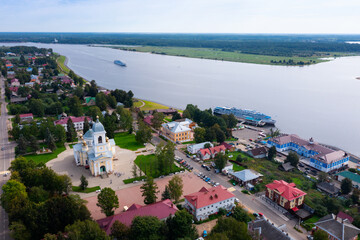 Panoramic aerial view of small Russian town of Myshkin in Yaroslavl Oblast on bank of Volga river on sunny summer day overlooking residential buildings, churches and river station