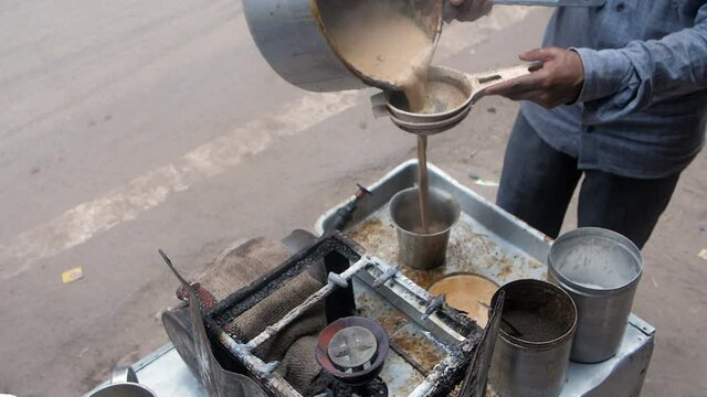 A local tea seller at a small shop serving freshly made tea in a big steel glass. Indian chai is being prepared in a big Degchi at a tea stall in Old Delhi - energizing  flavorful  hot  snacks