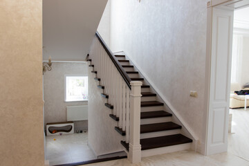 carved wooden staircase with brown steps and white railings and risers in a large house