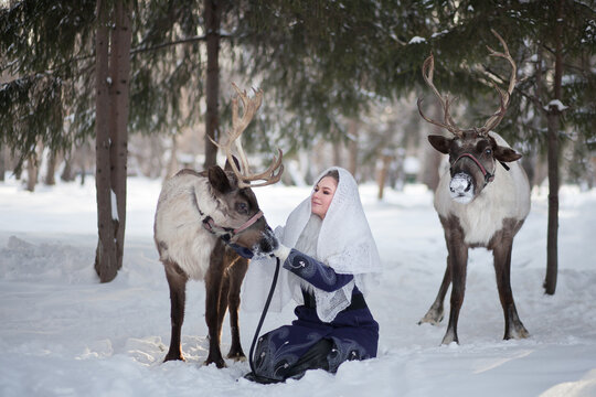 A girl walks in the winter with deer in the forest. Fairy tale. Reindeer. Fabulous photo session